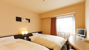 Habitación de hotel con dos camas, un escritorio, un televisor y una ventana con cortinas.