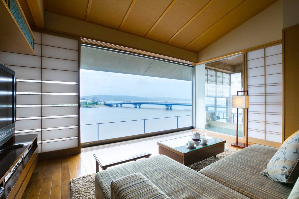 A modern room with a large window, a television, a sofa, and a small table.