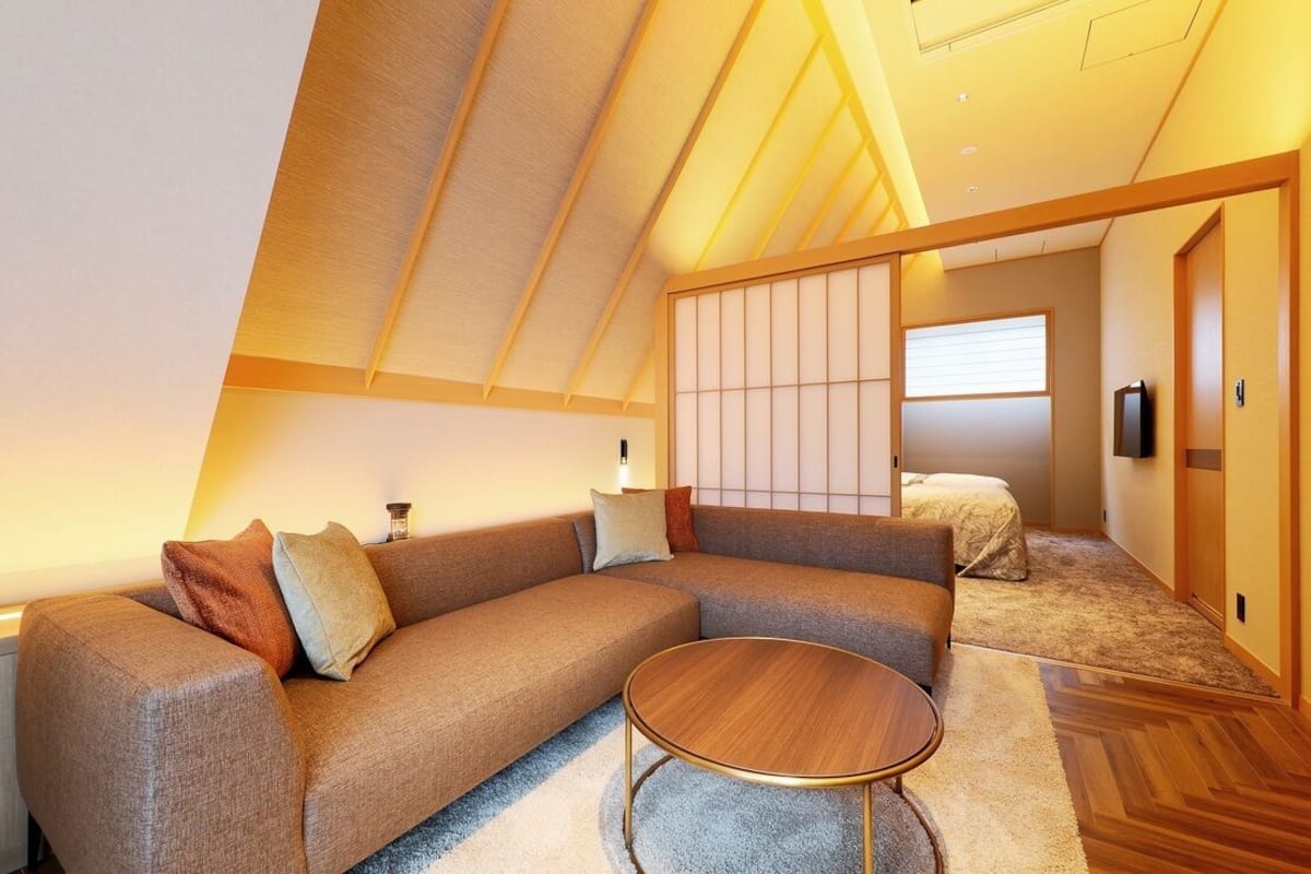 Un interior moderno con un sofá modular, una mesa redonda de centro y un panel corredero estilo shoji.