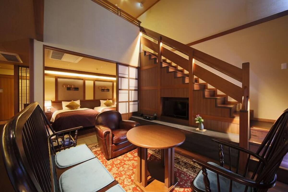 A traditional Japanese-style room with tatami flooring, a low wooden table, a sofa, and a fireplace.
