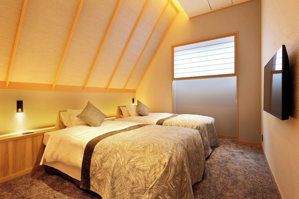 A bedroom with two beds, a window, and a TV.