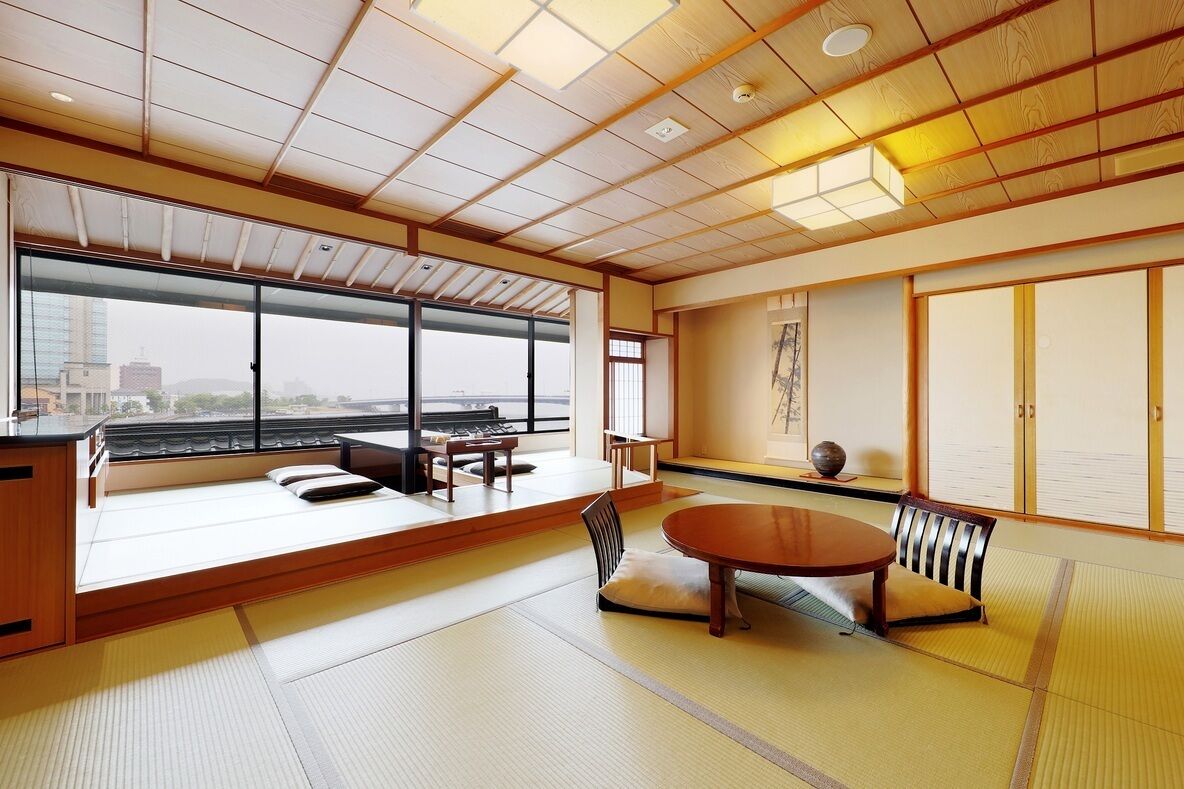 A tatami mat room with a tatami mat table, a low wooden desk, and a sliding door.