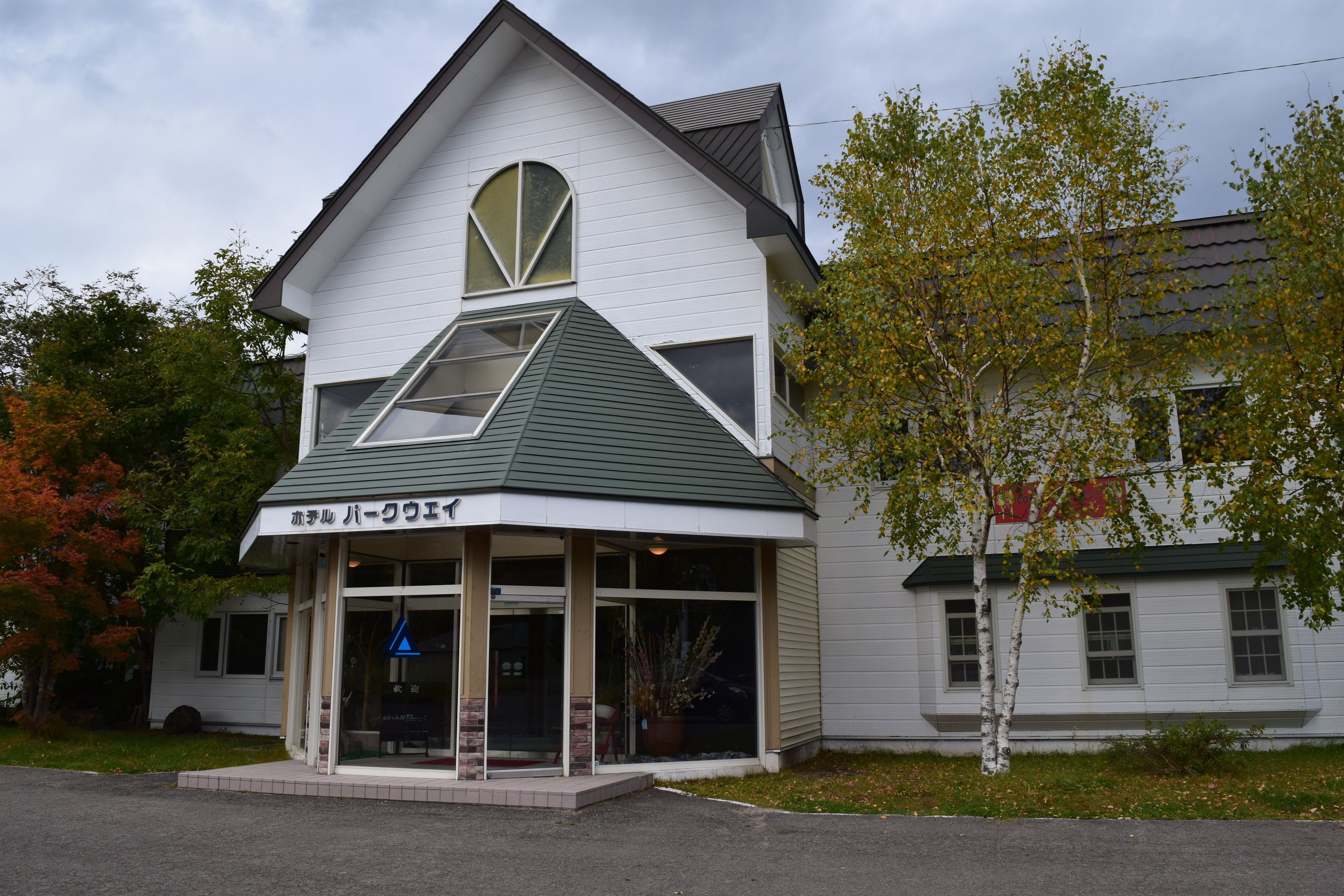 A two-story building with a green roof and a sign in a foreign language.