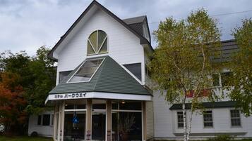 A two-story building with a green roof and a sign in a foreign language.