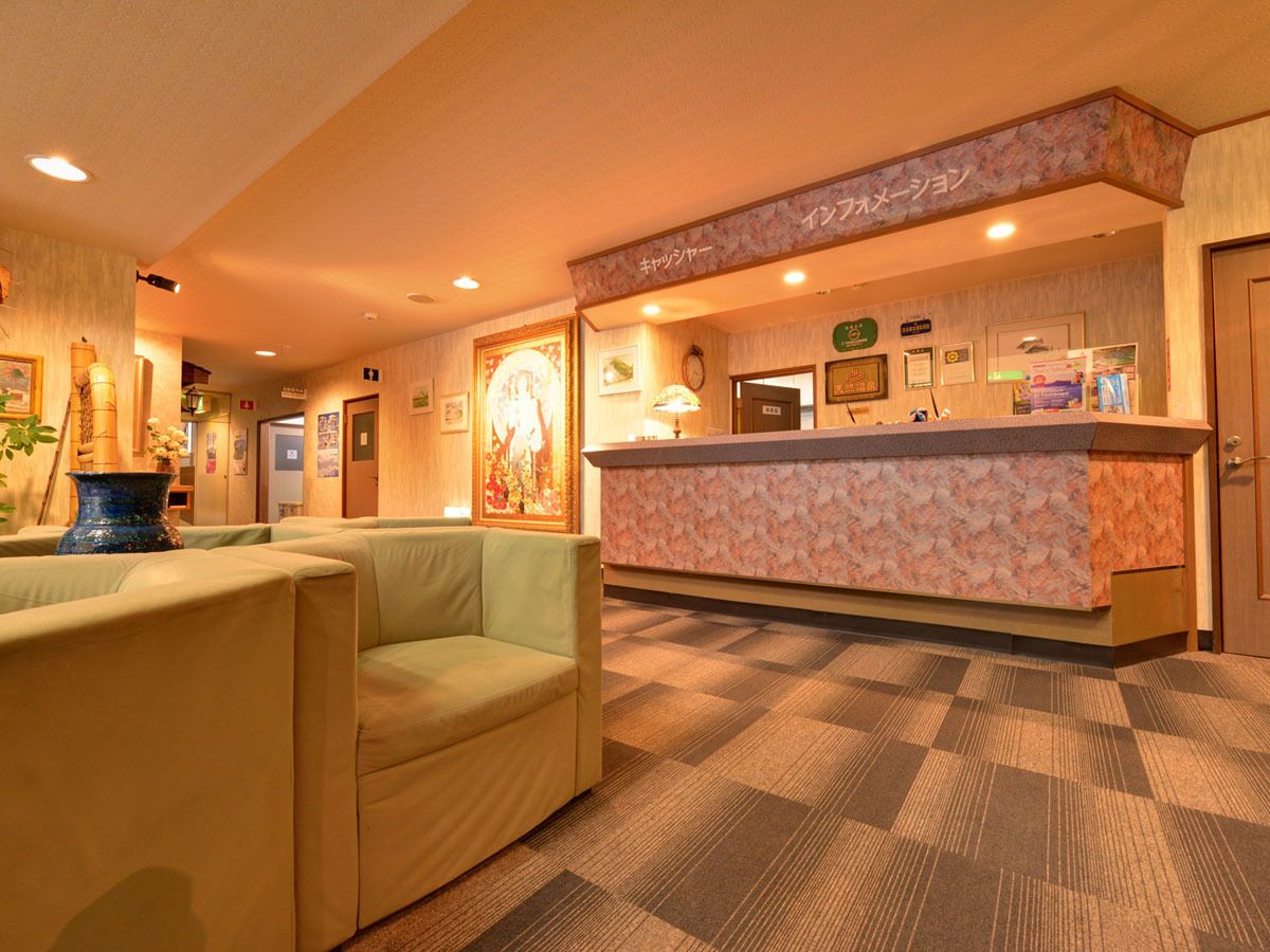 A hotel reception area with a counter, seating, and a carpeted floor.