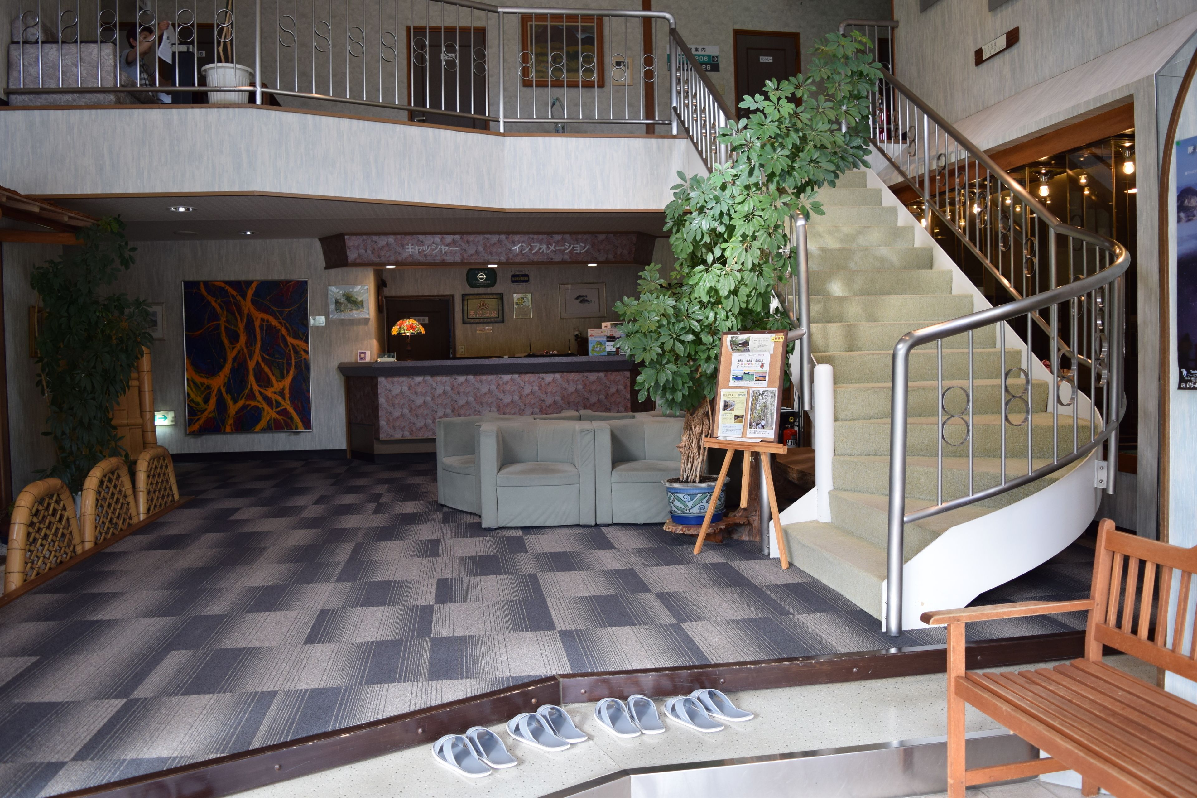 Un hall d’hôtel comprenant un comptoir d’enregistrement, un escalier et un espace détente.