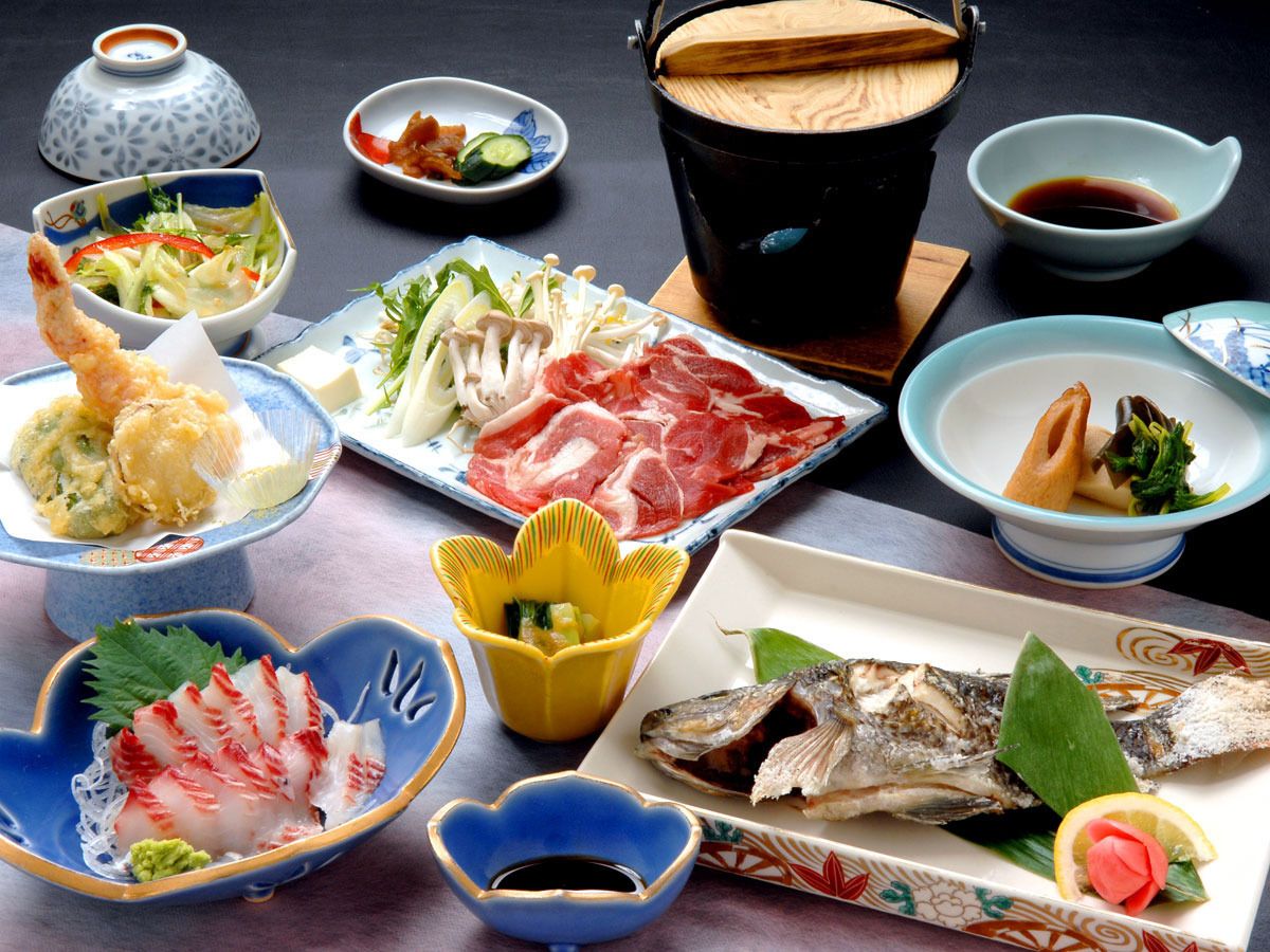 A variety of Japanese dishes including sashimi, tempura, and grilled fish, served on traditional ceramic plates and bowls.