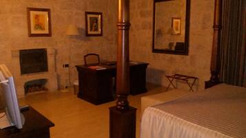 Una habitación con cama, escritorio, silla, chimenea y un espejo grande.