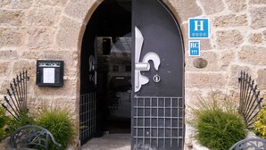 A stone building entrance with a black door, a reception sign, and a metal gate. - Señorio de Olmillos (Sasamon)