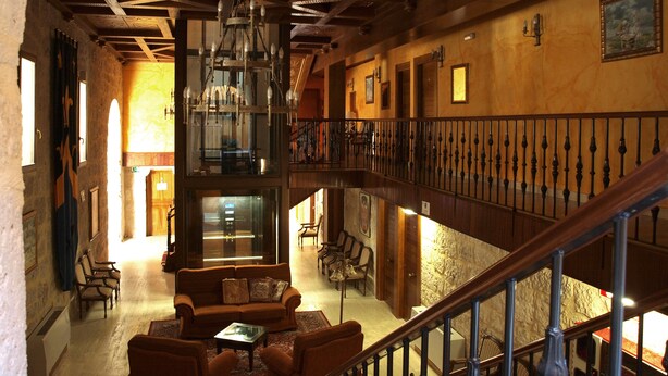 A spacious lobby with a high ceiling, a grand staircase, and a seating area with a sofa and chairs. - Señorio de Olmillos (Sasamon)
