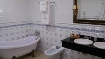 Un baño con bañera, bidé y lavabo con espejo superior.