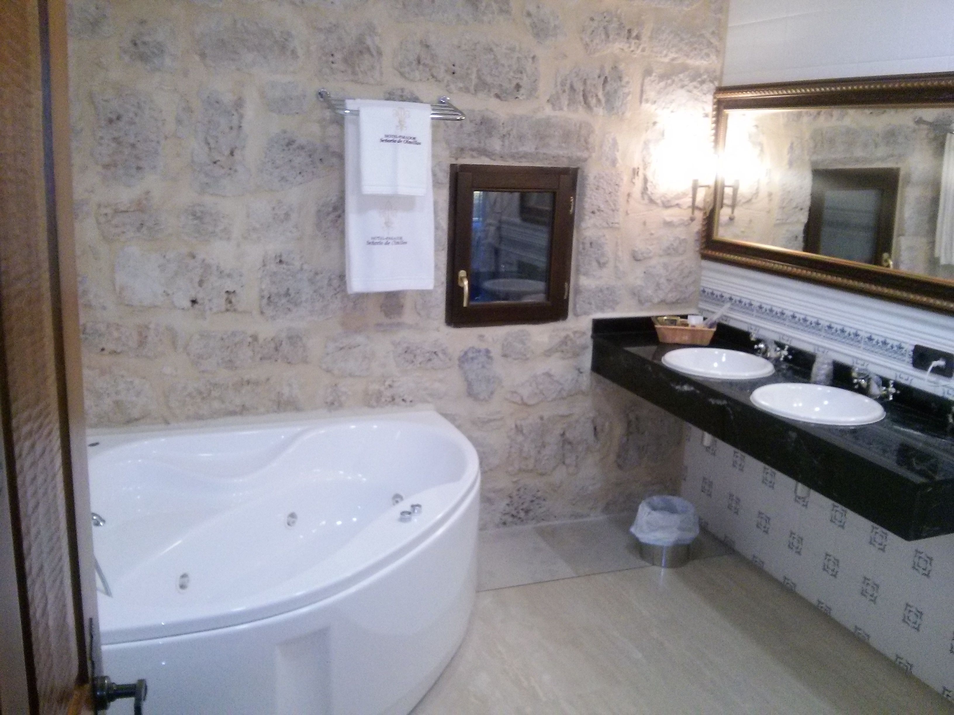 Un baño con bañera, dos lavamanos y un espejo.