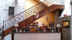 A bar area with a wooden staircase, stone walls, and a variety of liquor bottles. - Señorio de Olmillos (Sasamon)