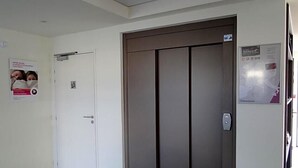 A hotel room with a white door, a large elevator, and a poster on the wall. - The Originals Access, Hôtel Cholet Gare (Cholet)
