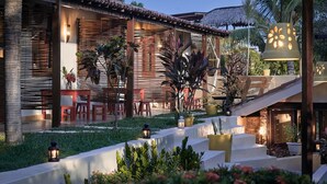 Un resort con mobiliario exterior, palmeras y una estructura de techo de paja.