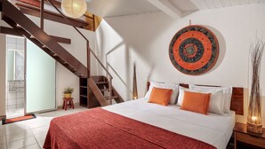 Un dormitorio con una cama grande, una escalera de madera y una obra de arte circular colgada en la pared.