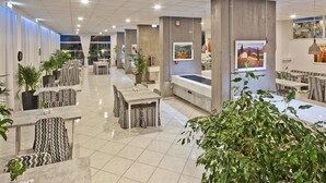 A spacious lobby with multiple seating areas, a reception desk, and artwork on the walls. - Miramare Bay Hotel (Karpathos)