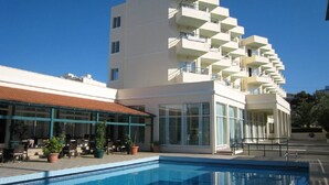 A modern hotel with a pool, outdoor seating, and a multi-story structure with balconies. - Miramare Bay Hotel (Karpathos)