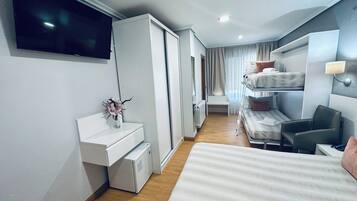 A hotel room with a bed, a desk, a chair, a TV, and a window with curtains.