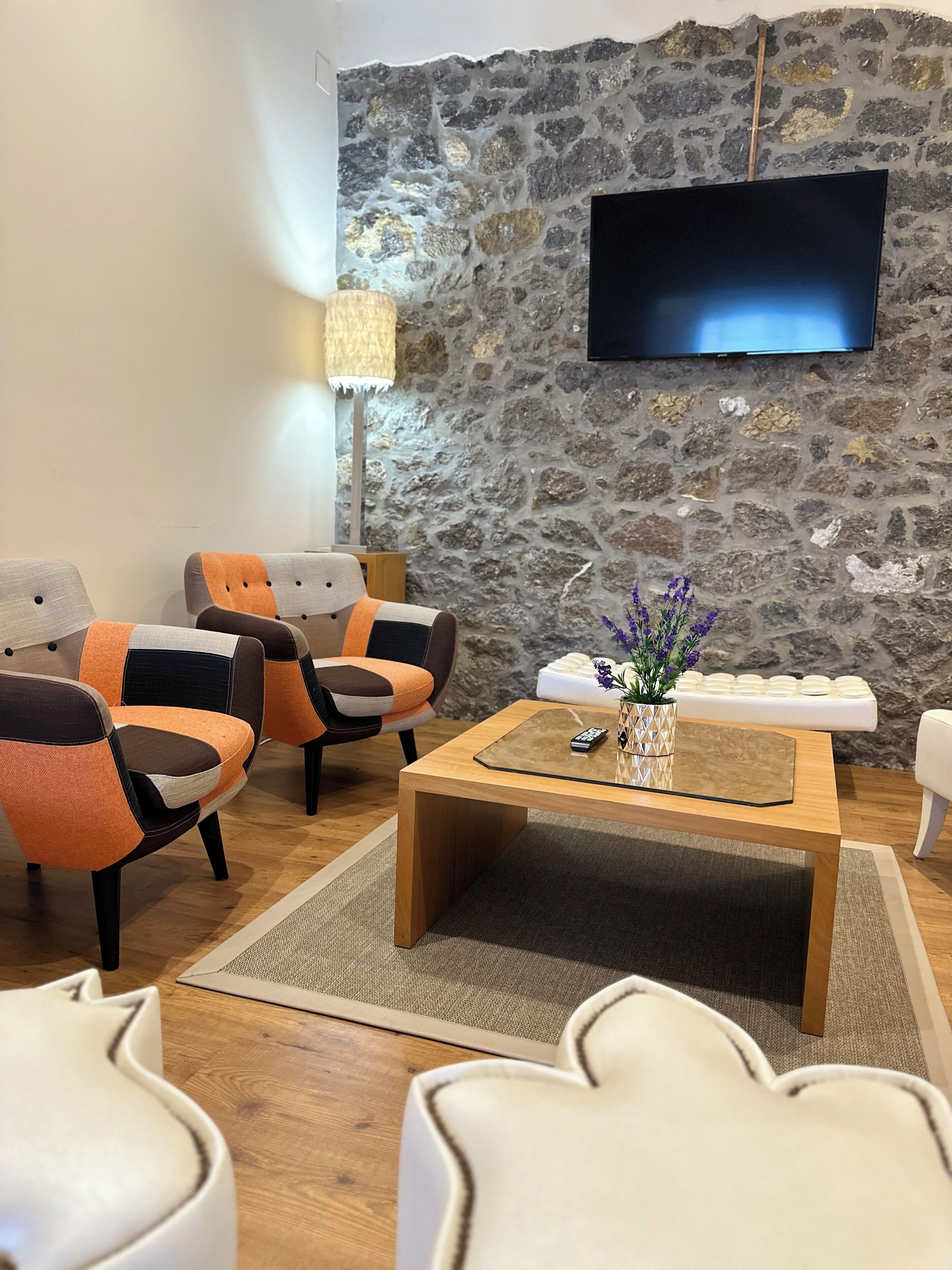 Una sala de estar moderna con pared de piedra, un televisor de pantalla plana y una mesa de centro con un jarrón de flores.