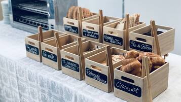 Cajas de madera etiquetadas con distintos tipos de pan y repostería sobre una mesa.