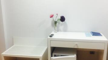 A small, white desk with a flat-screen TV mounted on the wall above it.
