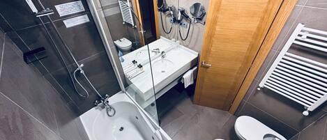 A modern bathroom with a bathtub, a toilet, and a shower area.