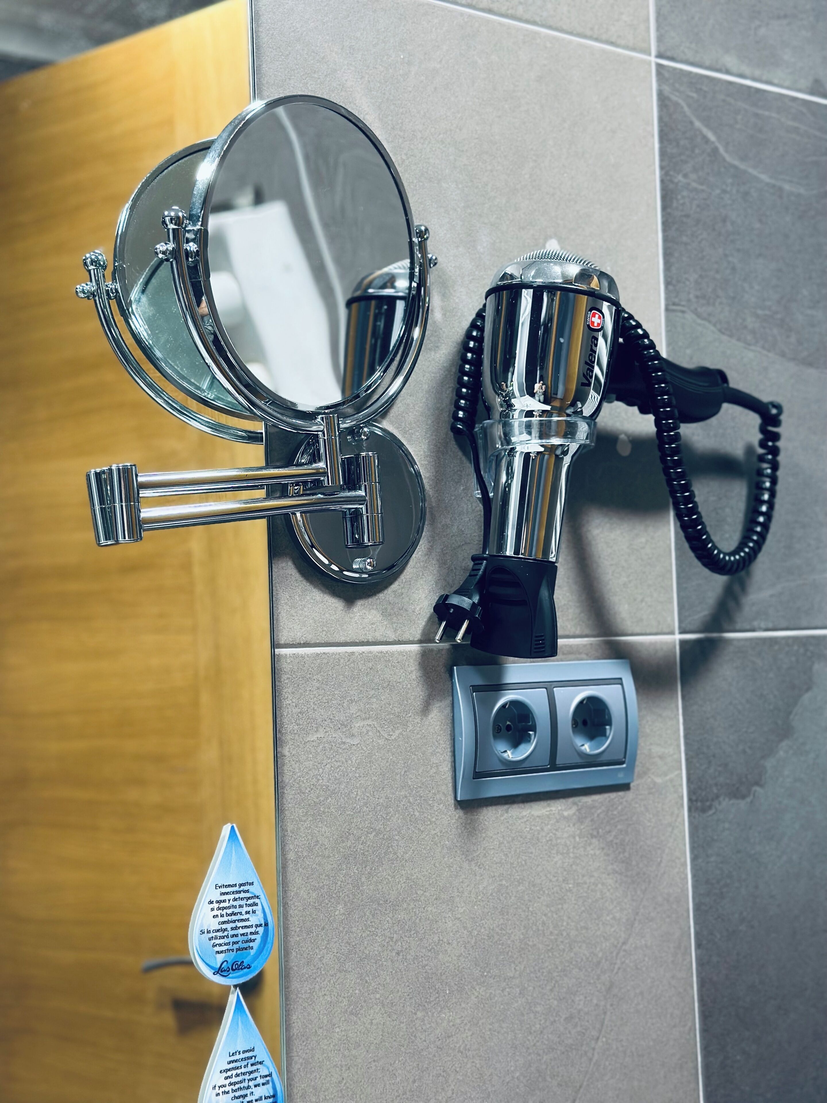 A bathroom with a mirror, a hairdryer, and a towel dispenser.