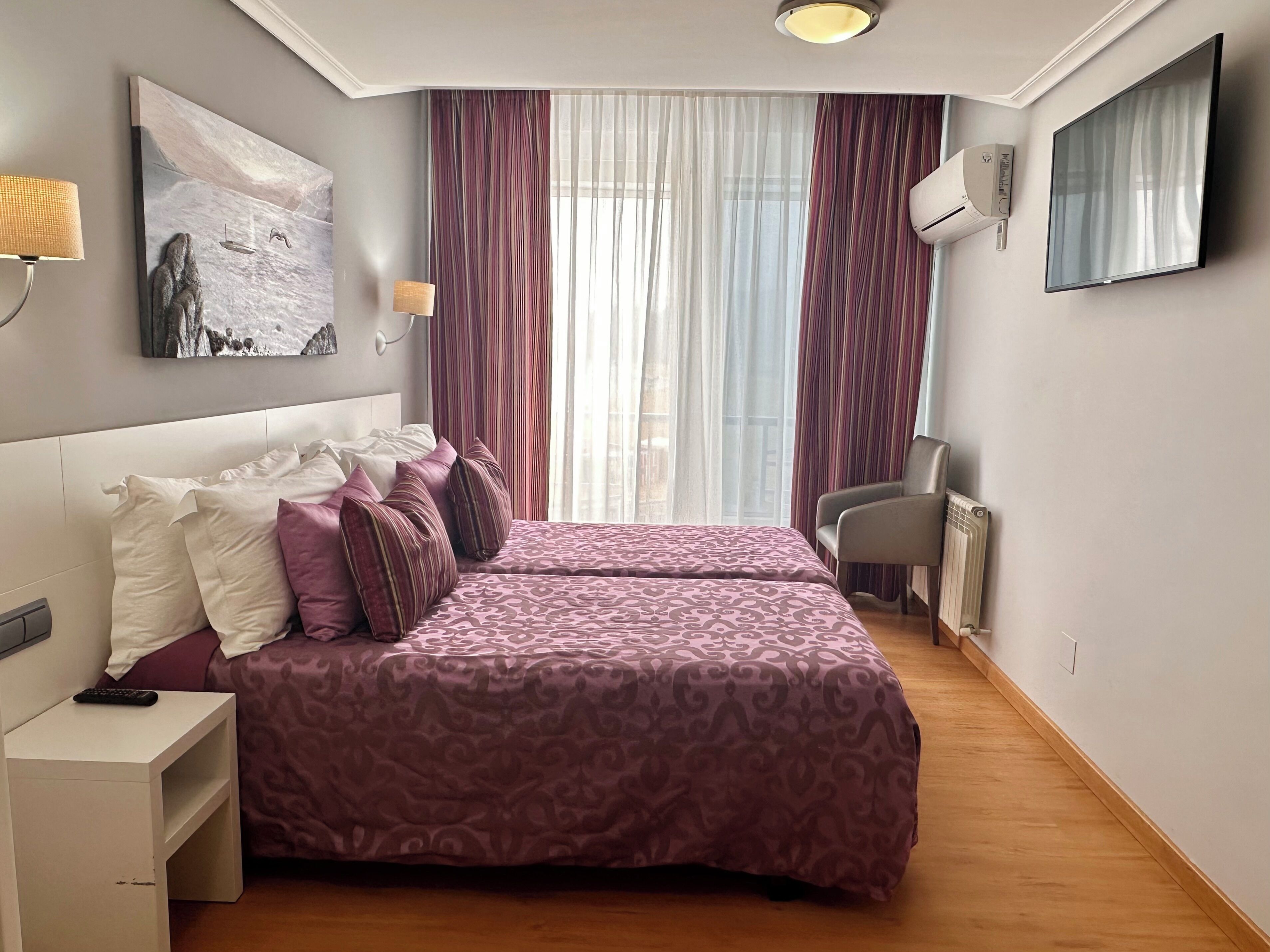 Habitación de hotel con cama doble, escritorio, silla, televisión y un cuadro en la pared.