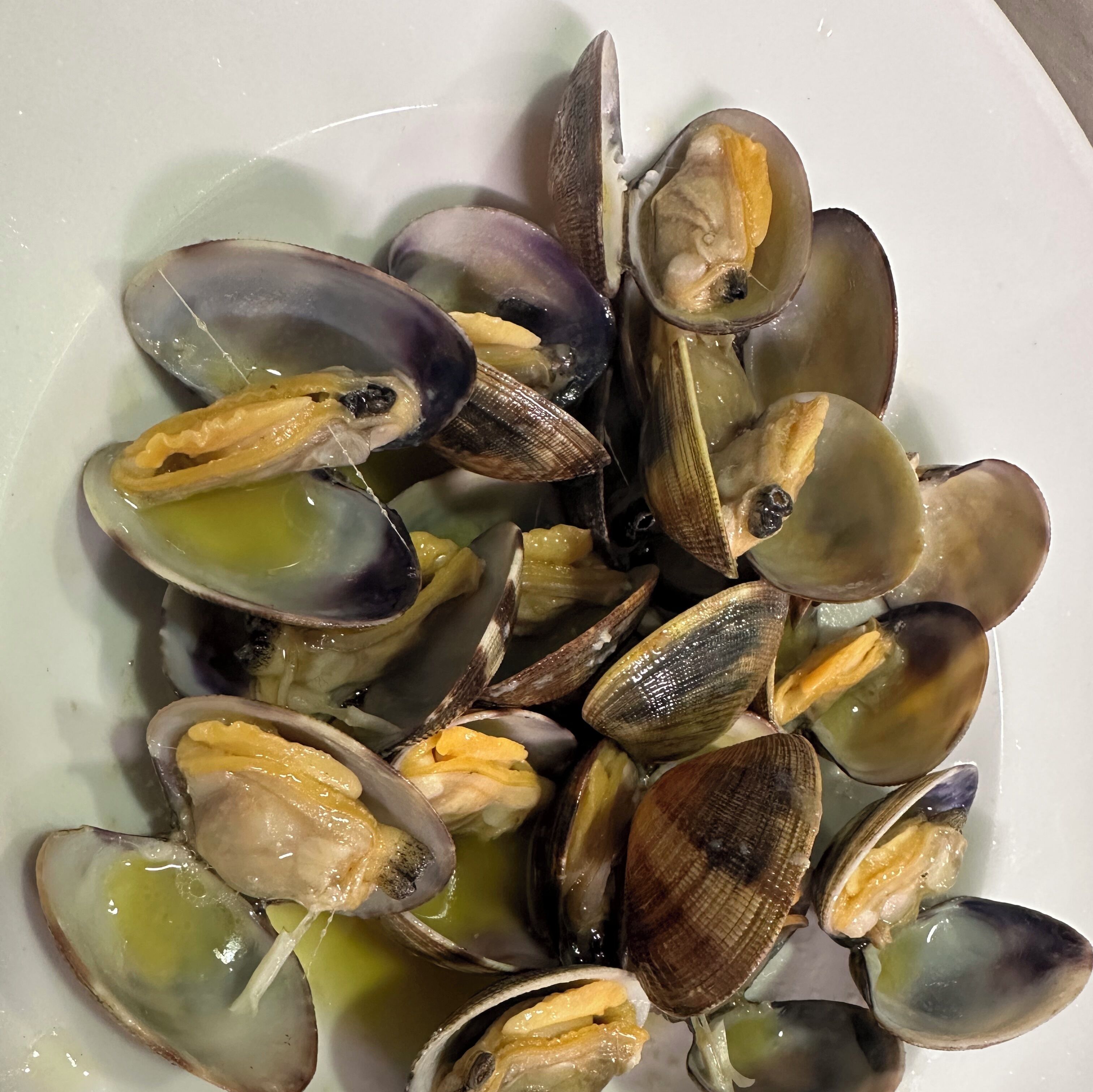 A bowl of clams with their shells open, revealing the meat inside.
