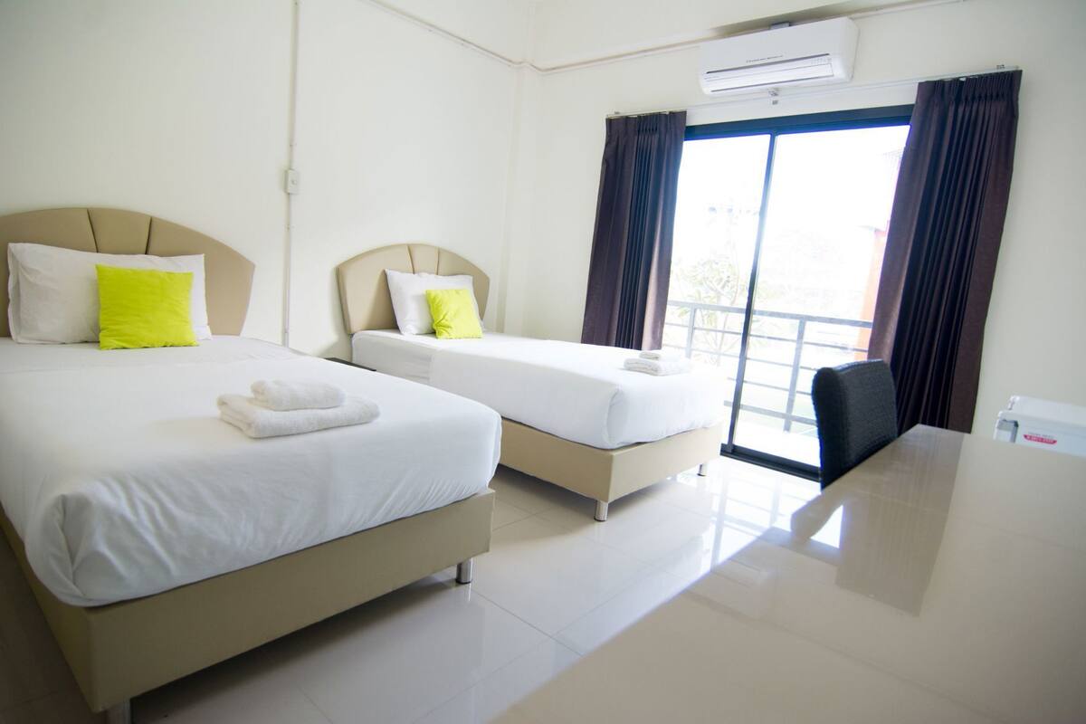 A hotel room with two beds, a desk, and a chair.