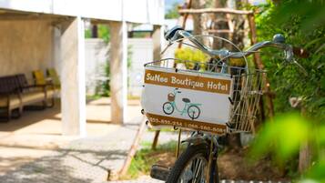 A bicycle with a basket labeled "SuNee Boutique Hotel" and contact numbers.