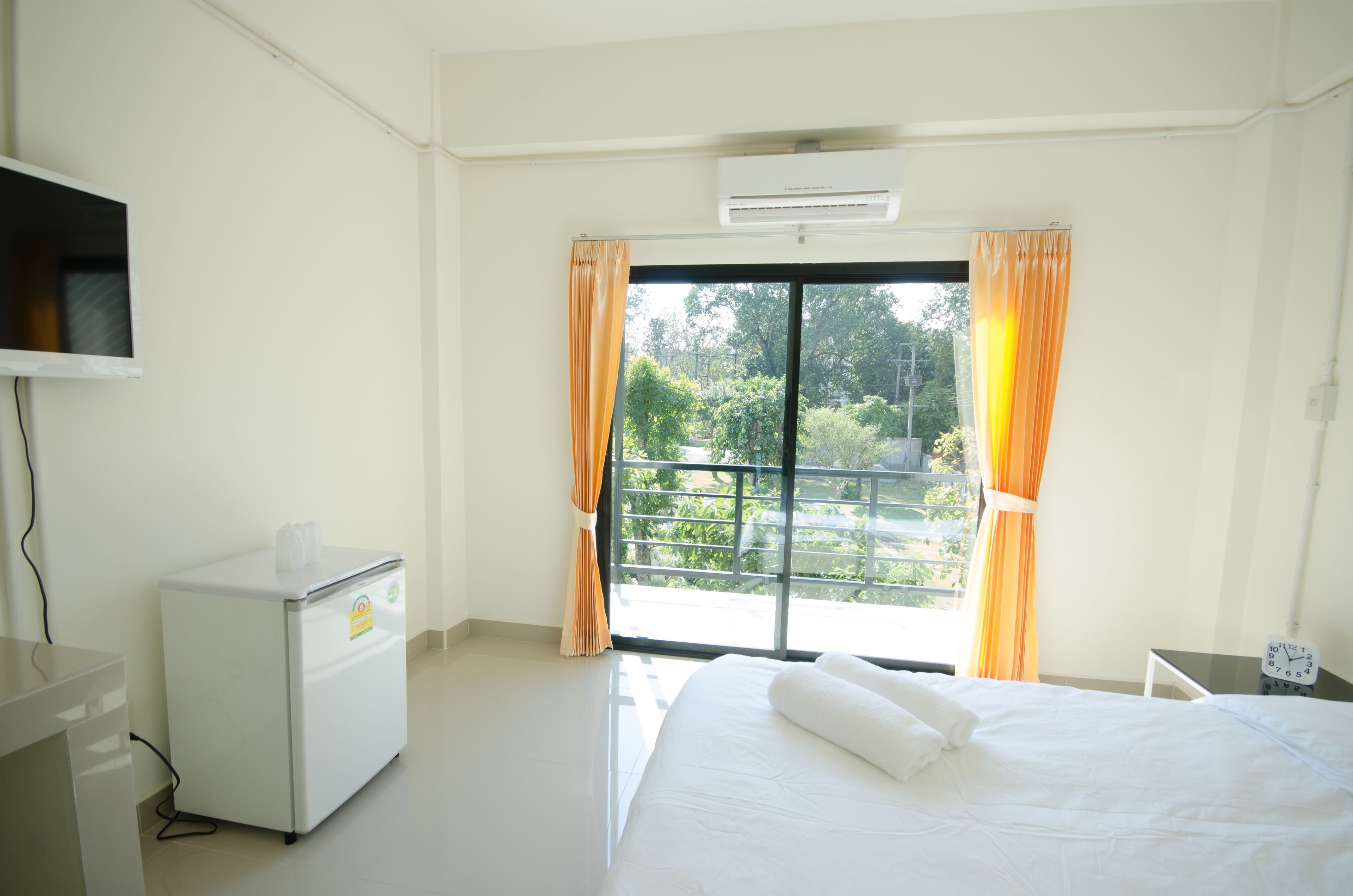 Una habitación de hotel con cama, un escritorio pequeño, un televisor y una ventana con cortinas.