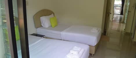 A hotel room with two beds, each with white linens and a pillow.