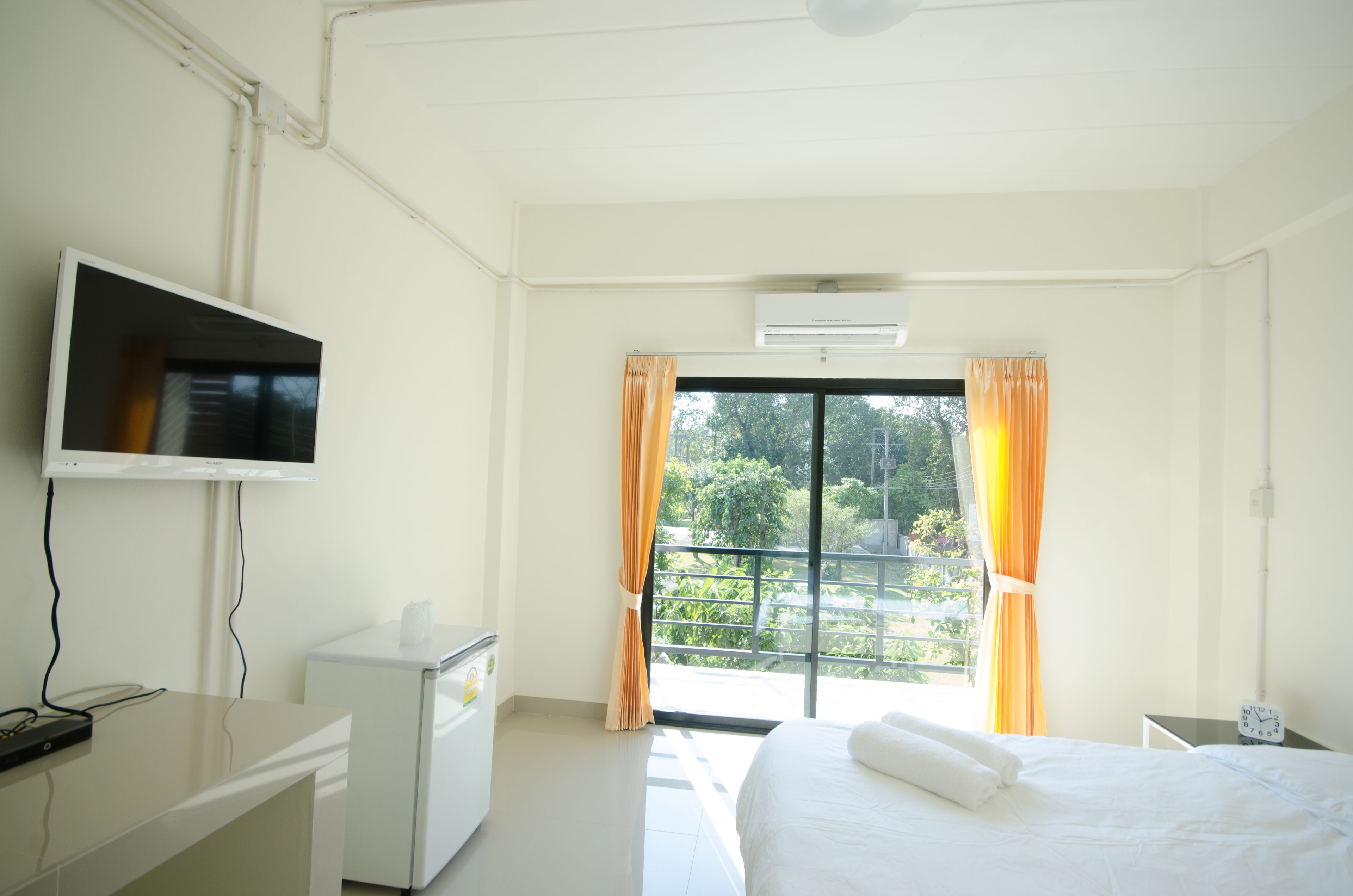 A hotel room with a bed, a desk, a television, and a window with curtains.