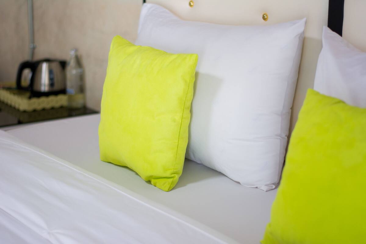 A bed with white and bright green pillows.