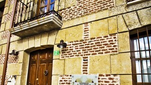 A building with a wooden door, a balcony with flowers, and a sign indicating it is a restaurant. - Posada Real del Buen Camino (Villanueva de Campean)