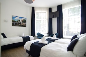 A hotel room with two beds, a chair, a table, and a painting of a canal scene. - Hotel Leidsegracht (Amsterdam)