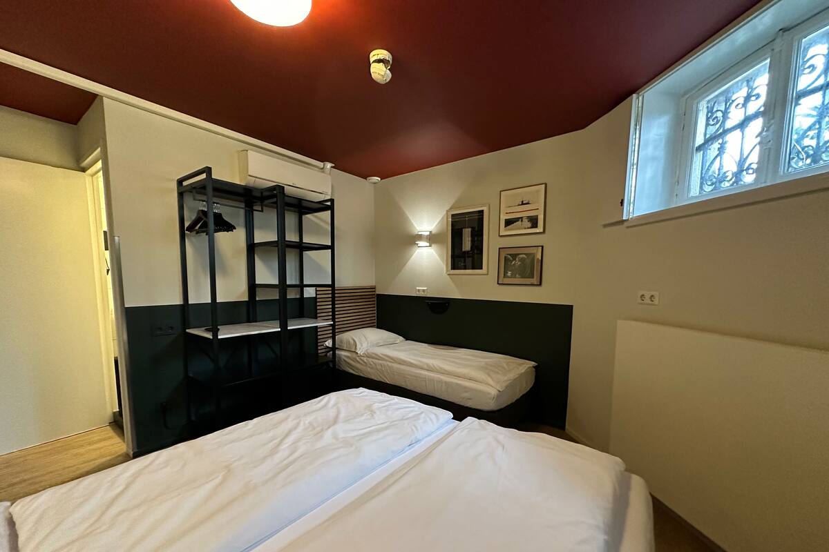 A room with bunk beds, a radiator, a window with decorative iron bars, and wall-mounted lights.