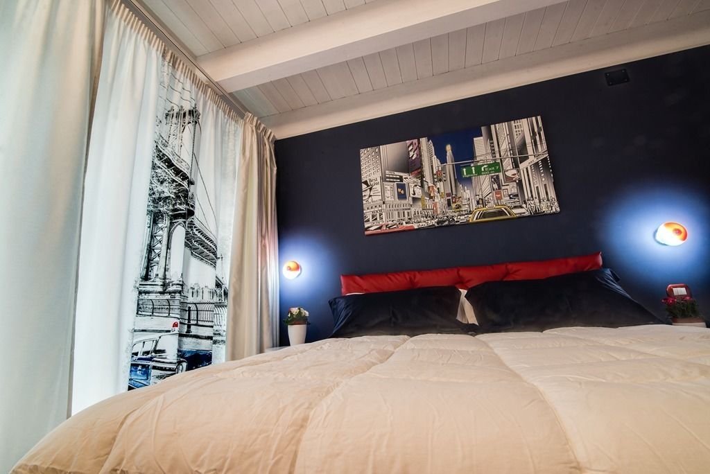 Ein Hotelzimmer mit einem großen Bett, einem Stadtbild an der Wand und zwei Wandleuchten zum Lesen.