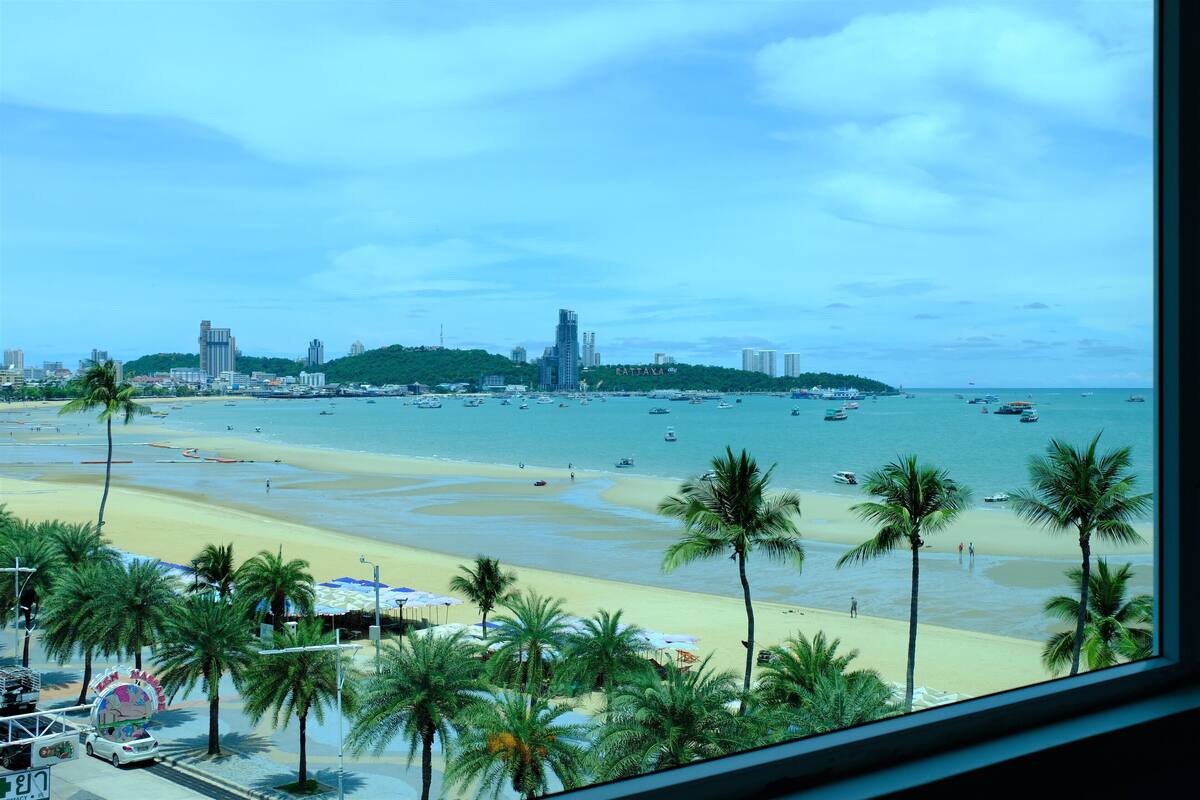 A beach with palm trees, a sandy shore, and boats in the water.