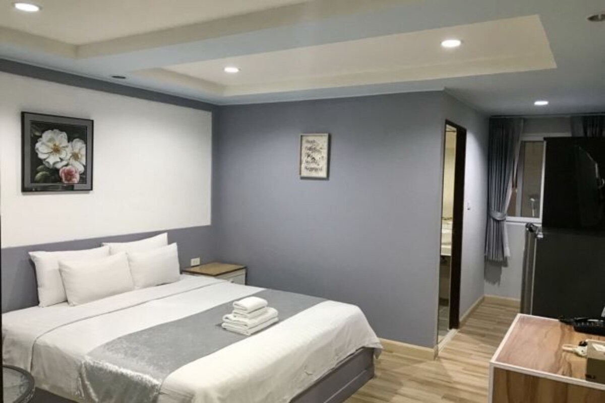 A modern hotel room with a bed, bedside tables, and a small desk.