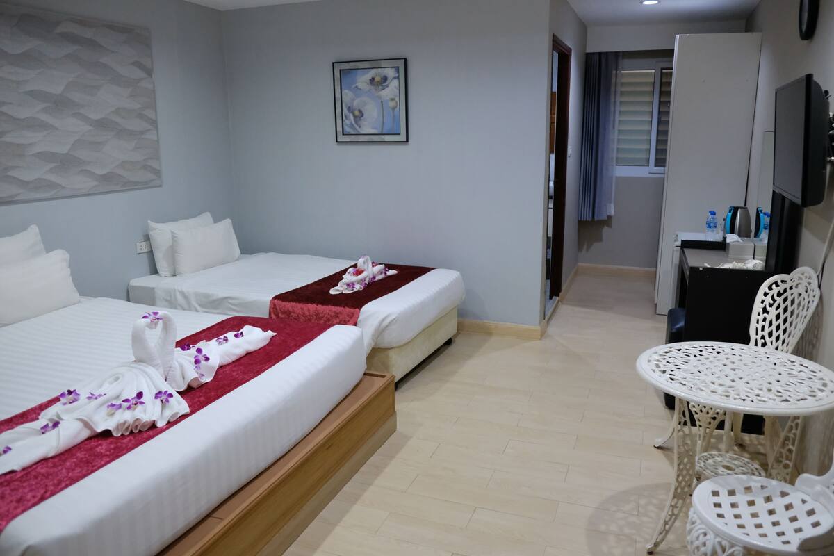 A hotel room with two beds, a small table, and a chair.