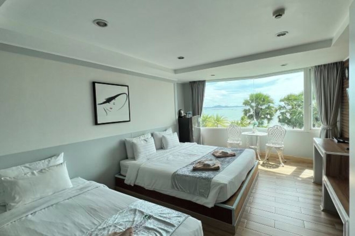 A hotel room with two beds, a balcony with a view, and a small seating area.