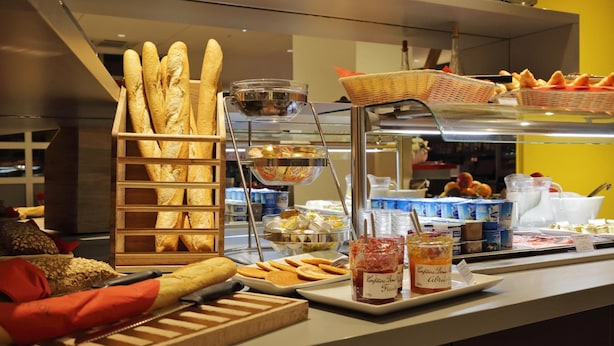 A breakfast buffet with various breads, pastries, and beverages.
