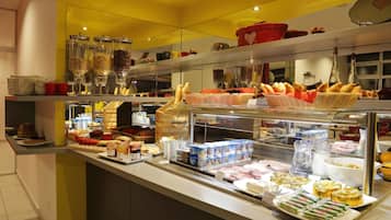 Un buffet proposant une variété de plats, notamment du pain, des pâtisseries et des produits laitiers.