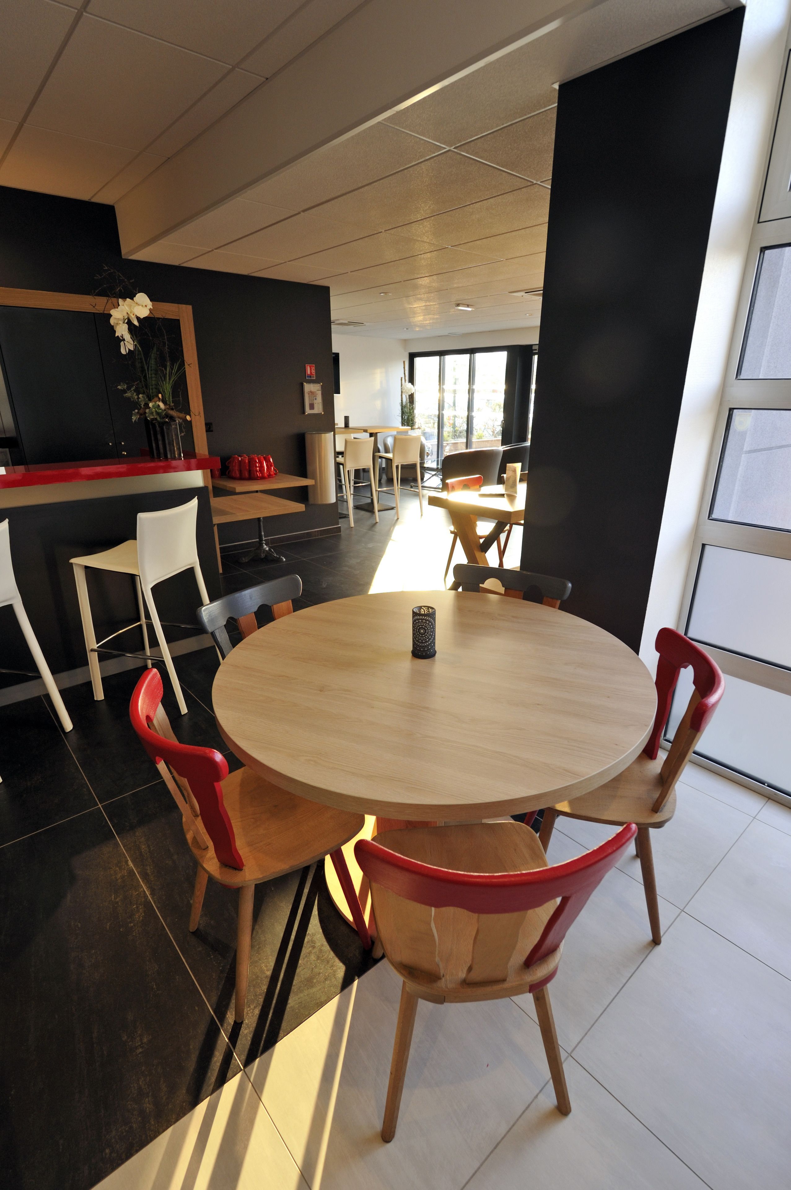 Un comedor moderno con una mesa redonda, sillas de madera y un sillón rojo.