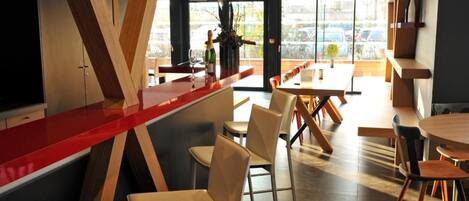 A modern interior with a bar area, seating, and large windows offering a view.