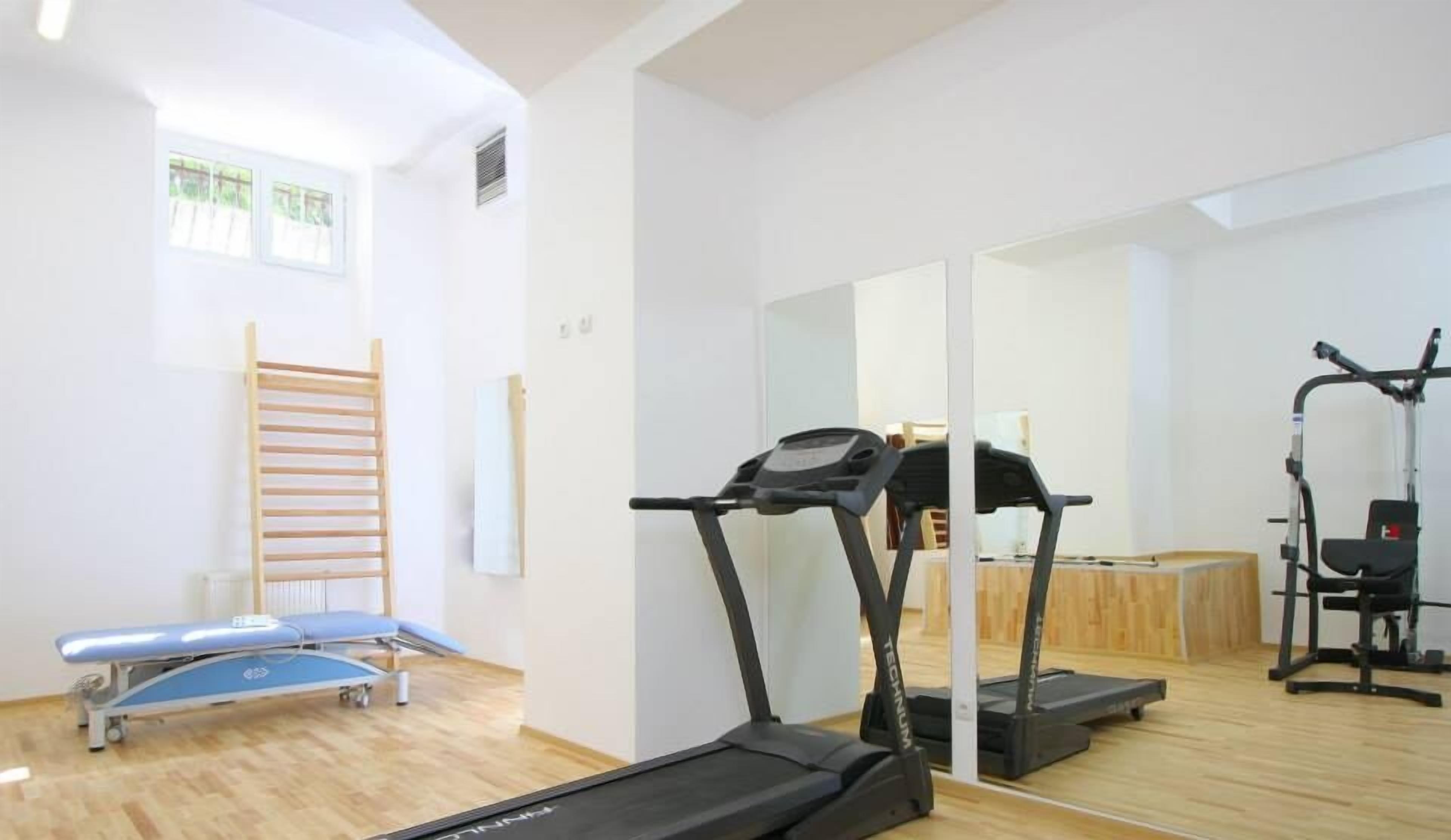 A fitness room with a treadmill, exercise bike, and a massage table.