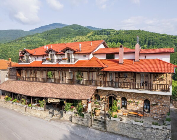A hotel with multiple balconies, a stone facade, and a red-tiled roof.